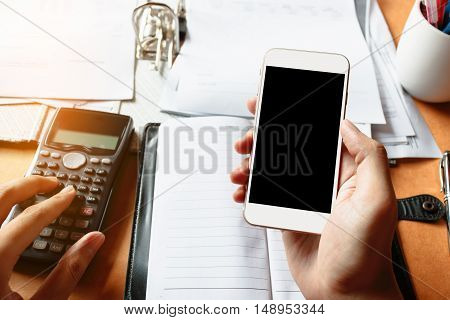 Close up of businessman using mobile phone with blank sceen for searching data and calculator counting making notes and in office or home.