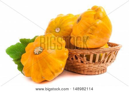 yellow pattypan squash with leaf in a wicker basket isolated on white background.