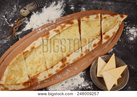 Turkish Pizza Is Called Pide. Dish With Pide With Cheese On A Dark Table, Sprinkled With Flour.