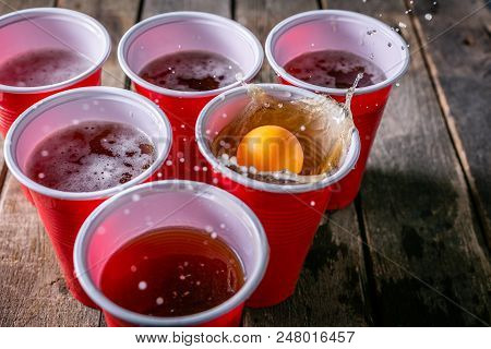 College Party Sport - Beer Pong Table Setting With Plastic Cups, Rustic Wood Background