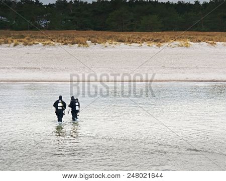 Prerow Germany - January 25 2018: Two Winter Scuba Divers Walking With Their Gear In Shallow Water T
