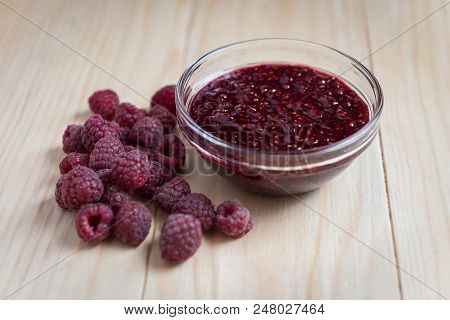 Homemade Raspberry Jam In A Glass Bowl With Fresh Ripe Organic Raspberries On A Wooden Table