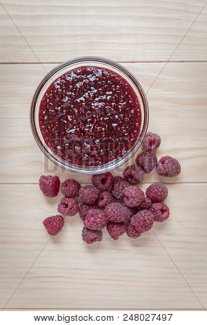 Homemade Raspberry Jam In A Glass Bowl With Fresh Ripe Organic Raspberries On A Wooden Table