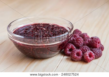 Homemade Raspberry Jam In A Glass Bowl With Fresh Ripe Organic Raspberries
 On A Wooden Table