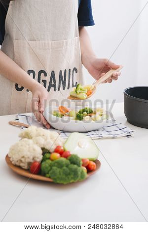 Woman In Kitchen Cooking Stir Vegetables On Pan And Tasting.
