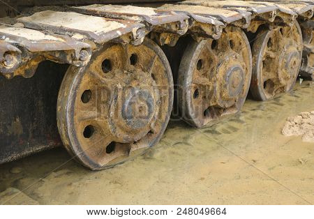 Old Iron Caterpillar In Wet Sand. Rusty Steel Wheels And Caterpillar Tape Of A Large  Bulldozer, Tan