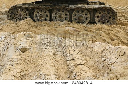 Old Iron Caterpillar In Wet Sand. Rusty Steel Wheels And Caterpillar Tape Of A Large  Bulldozer, Tan