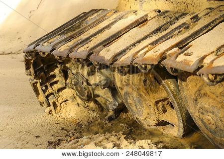 Old Iron Caterpillar In Wet Sand. Rusty Steel Wheels And Caterpillar Tape Of A Large  Bulldozer, Tan