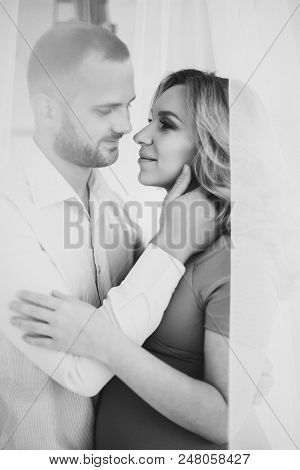 Black And White Portrait Of Couple, Embracing Each Other, Looking Face To Face And Smiling. Pregnant