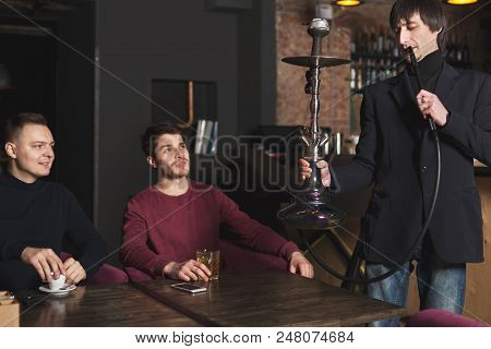 Two Confident Businessmen Drinking Whiskey And Ordering Hookah, Having Informal Business Meeting At 