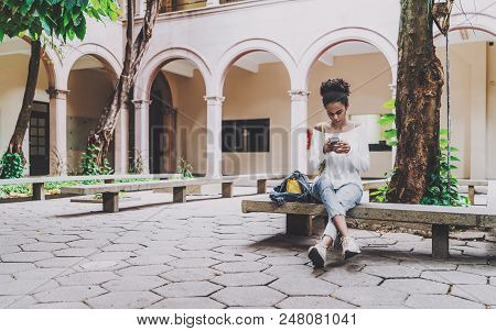 Young Cute Brazilian Undergraduate Girl Is Sitting In The Courtyard Of Her Univercity On The Concret