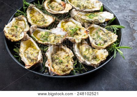 Barbecue overbaked fresh opened oyster with garlic and herbs offered as top view on a tray 