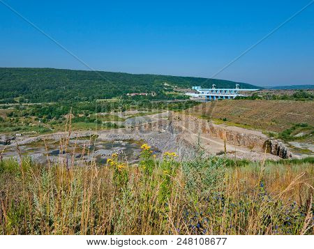 Quarry, Dam And Hydroelectric Plant Against The Backdrop Of A Summer Meadow, Green Mountains And A C