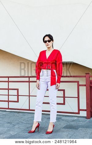 Attractive Young Fashionable Lady In Sunglasses Wearing Red Highheel Shoes Standing In The City Cent