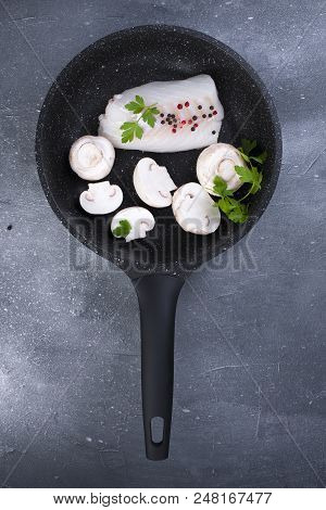 Preparation Of A Seafood Dinner. Fillet Of White Fish In A Black Frying Pan With Mushrooms And Spice