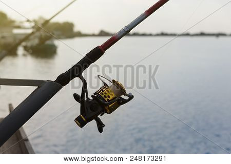 Fishing Rod With Spool Spinning Stands On The Bracket, Close-up, Fishing On The River