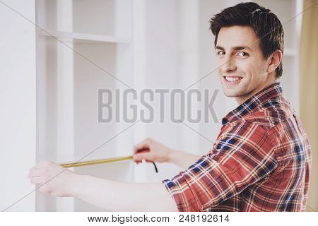 Young Smiling Man In Checkered Shirt Installing Furniture In New Home. Moving To New House. Repair I