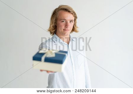 Positive Handsome Guy Presenting Gift. Young Caucasian Man In White Shirt Holding Present Box And Po