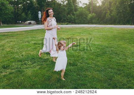 Joyful Woman In Light Dress Running Catching Up Have Fun With Little Cute Child Baby Girl On Green G