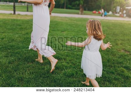 Cropped Little Cute Child Baby Girl Running Catching Up With Joyful Woman In Light Dress On Green Gr