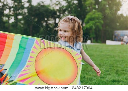 Smiling Little Cute Child Baby Girl In Denim Dress Walking, Play With Colorful Kite And Have Fun In 