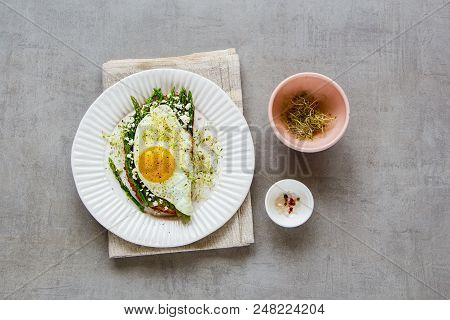 Flat Lay Of Green Aspargus, Fried Egg, Feta Cheese And Micro Greens Spring Sandwich On Plate Over Li