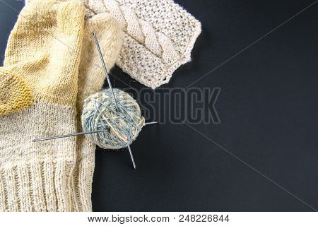 A Ball Of Wool With Knitting Needles And Socks On A Gray Table. Needlework
