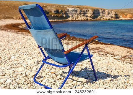 Folding Chair Stands On The Beach, The Concept Of Vacation And Travel