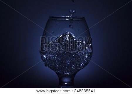 Simple Still-life Photo Of Whisky Glass, Water Jet And Dim Colour Light
