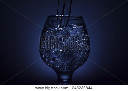 Simple Still-life Photo Of Whisky Glass, Water Jet And Dim Colour Light
