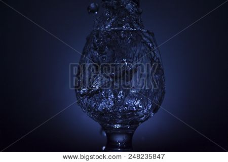 Simple Still-life Photo Of Whisky Glass, Water Jet And Dim Colour Light