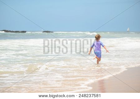 Happy Girl In Purple Swimsuit Running On The Beach In The Waves, Family On Vacation, View From Behin