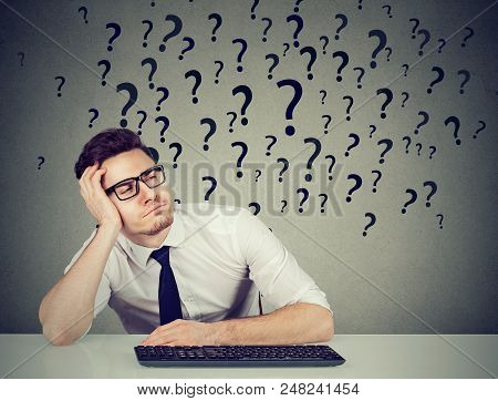 Young Procrastinating Office Employee Sitting In Laziness At Desk And Looking Away In Ignorance.