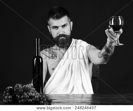 Sommelier Tastes Drink. Man With Beard Holds Glass Of Wine On Brown Background. Winemaking And Degus