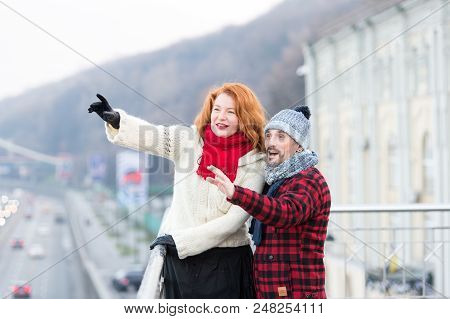 Aged Couple Happy Standing On Bridge. Woman And Man Point To Other Side. Couple Of Tourists Showing 