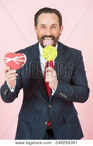 Businessman With Lollipop And Heart In Hands. Portrait Of Handsome Man Holding Candy And Opened Mout