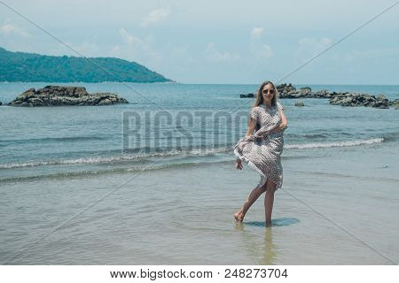 Handsome Girl On The Beach Background. Portrait Of A Woman In White Clothes On The Sea