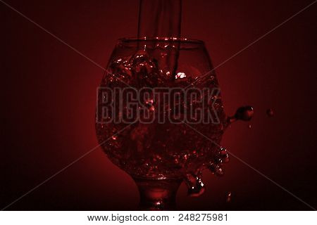 Simple Still-life Photo Of Whisky Glass, Water Jet And Dim Red Light