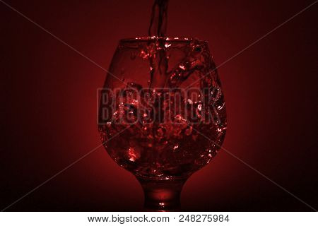 Simple Still-life Photo Of Whisky Glass, Water Jet And Dim Red Light