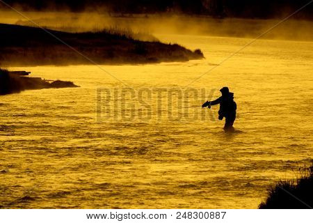 Silhouette of Fishing Flyfishing rod reel in river with golden sunlight