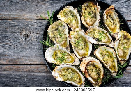 Barbecue overbaked fresh opened oyster with garlic and herbs offered as top view on a tray with copy space left