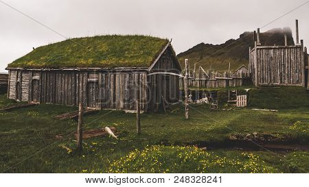 Old Viking Village In Iceland With Foggy Hill. Old Wooden Buildings Covered Grass