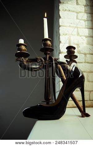 Design Shoe Of Black Leather Stand On High Heel With Snake Wrapped Around Candle Holder. Design Foot