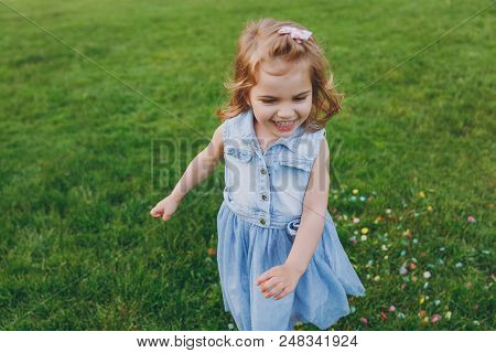 Smiling Little Cute Child Baby Girl In Denim Dress Walking And Running, Have Fun On Green Grass Lawn