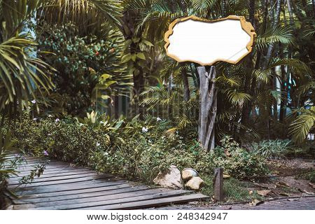 Blank Angular Information Banner On The Top Of A Wooden Pole With Tropical Trees Behind; Empty Mock-