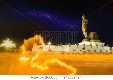 Beautiful Milky Way And Big Buddha Statue At Night And Moving Candle Light In Makha Bucha Day.