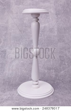 An Original White Candlestick With Catved Leg Is Situated On The Grey Background.