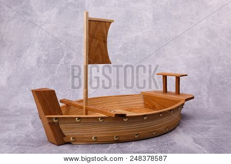 A Wooden Tray In The Form Of A Ship With Sails And Oar Is Situated On The Gre Background.