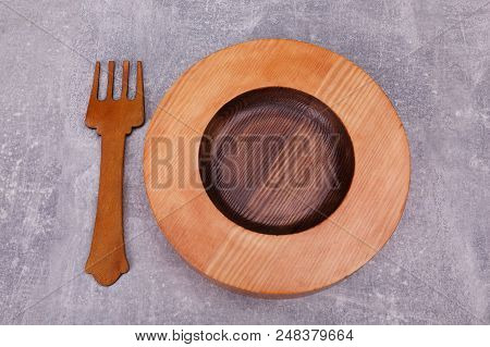 A Wooden Saucer Is Layed Out With A Decorative Wooden Fork, Situated On The Kitchen Tabletop.