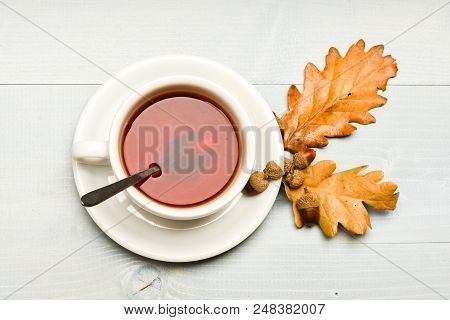 Mug Filled With Black Brewed Tea, Spoon And Autumn Fallen Leaves On White Background. Autumn Drink C